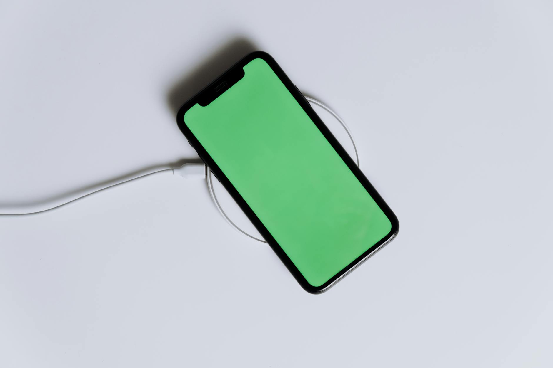 Smartphone positioned on wireless charging pad with thick protective case