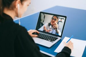 Microsoft Teams Adds Real-Time Language Translation for Enterprise Users Business professionals in a video conference meeting with laptops and screens displaying remote participants