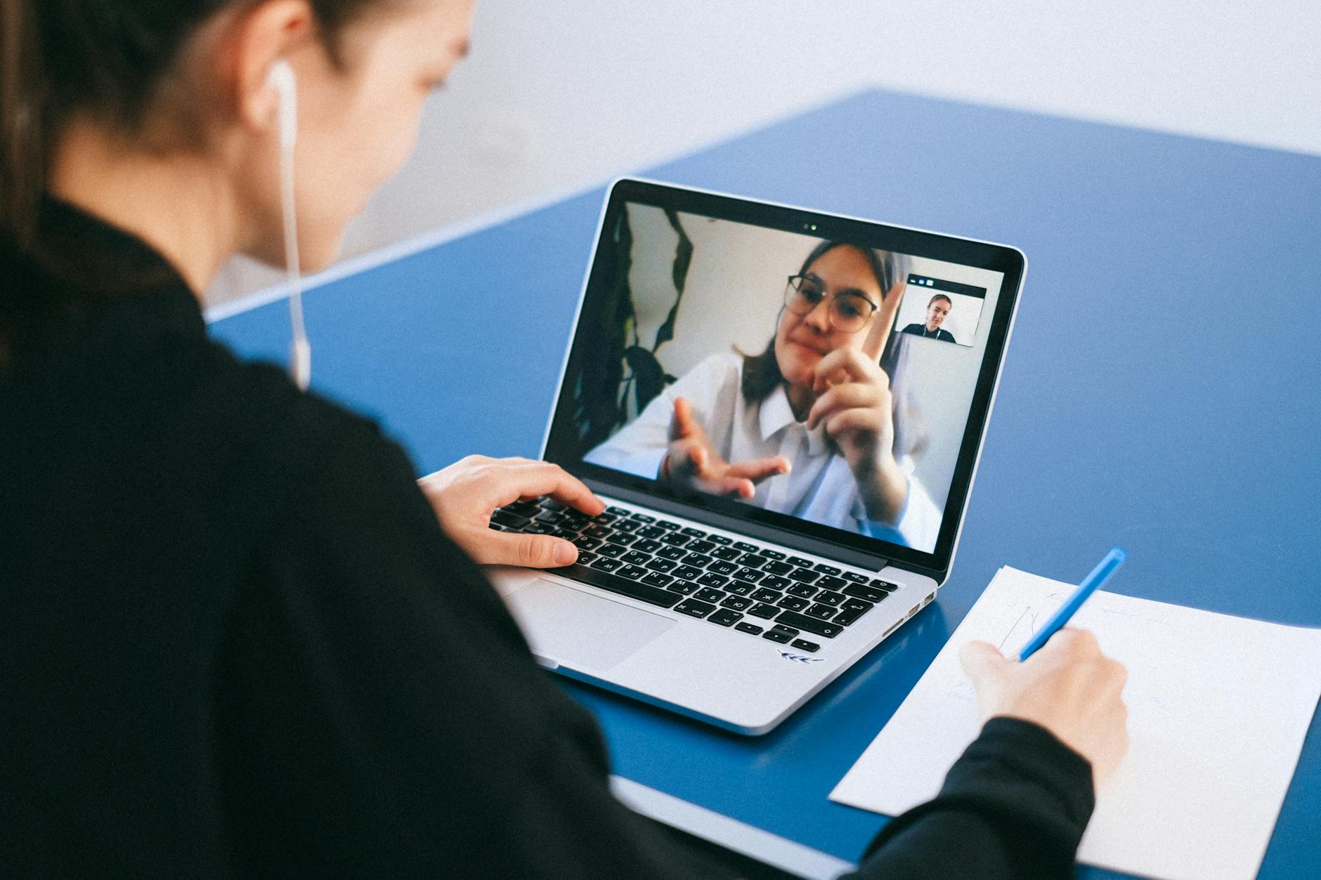 Business professionals in a video conference meeting with laptops and screens displaying remote participants