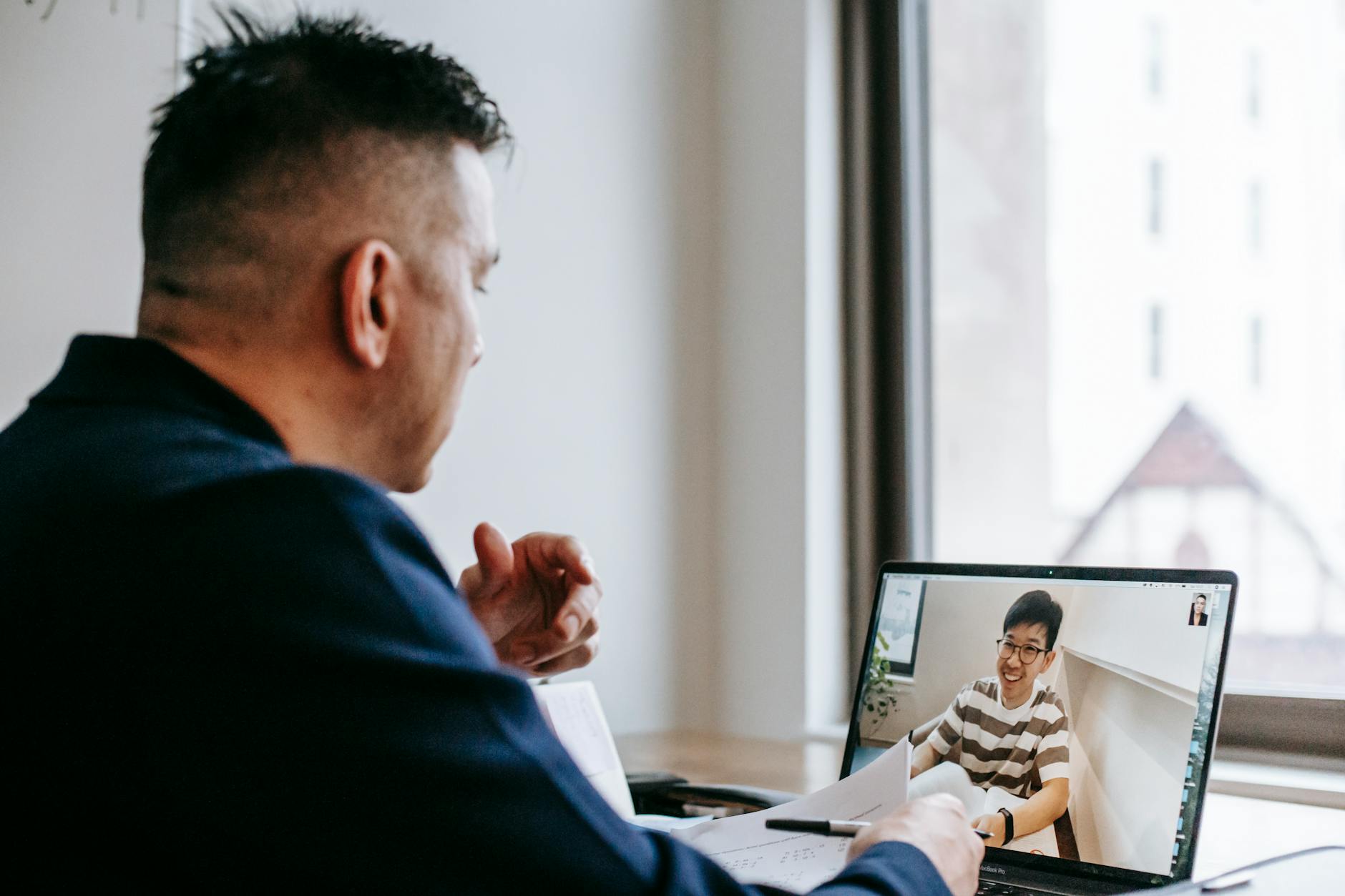 Person participating in video conference call using wireless earbuds at home office setup