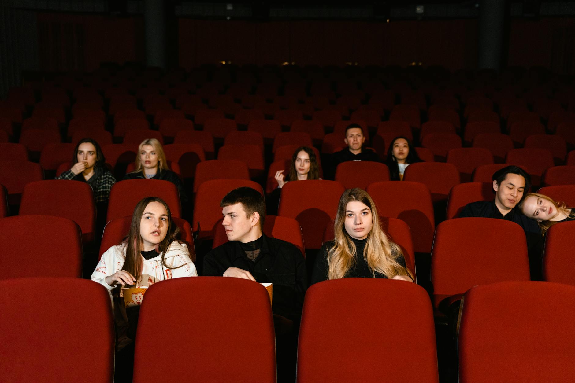 Empty movie theater with red seats facing a large screen