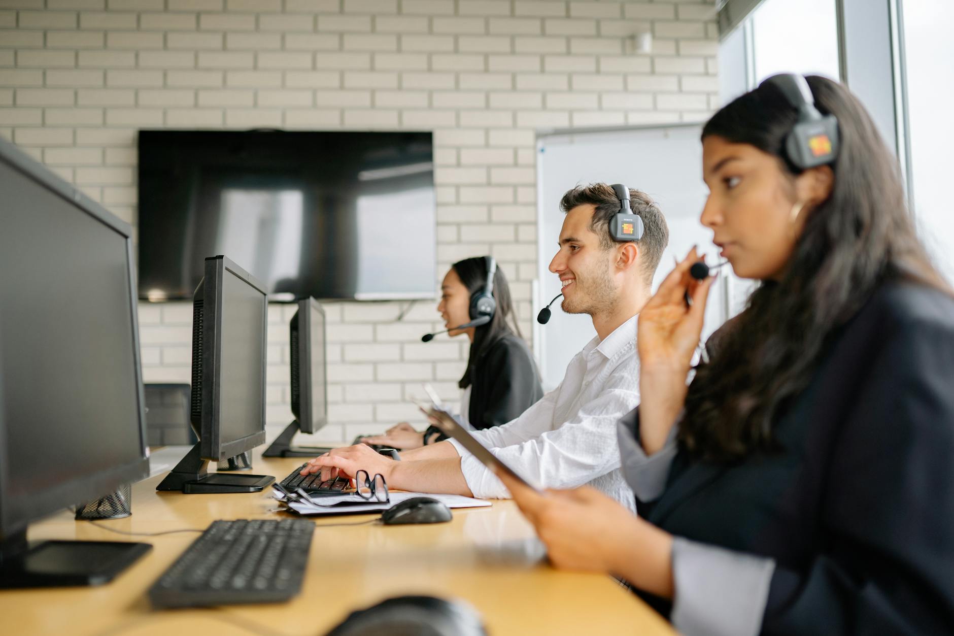 Customer service representatives working at computers in a modern office environment