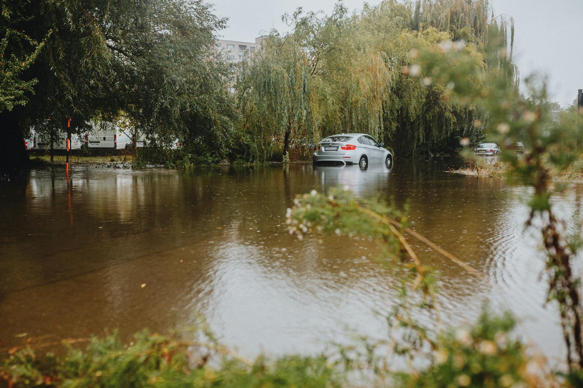 Cars navigating through flooded city street with standing water