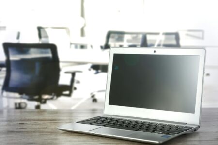 Modern laptop computer open on wooden desk workspace