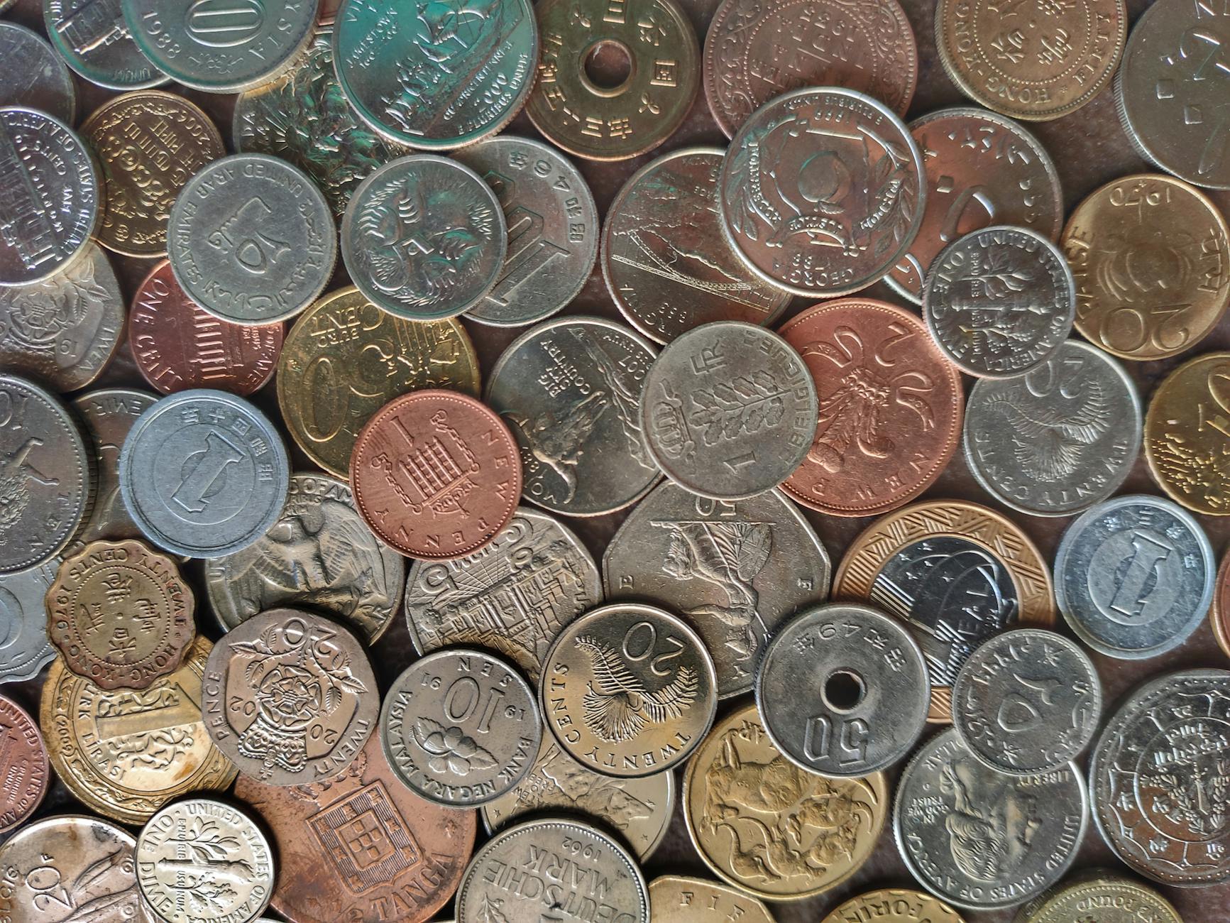 Person examining coins with magnifying glass for collecting