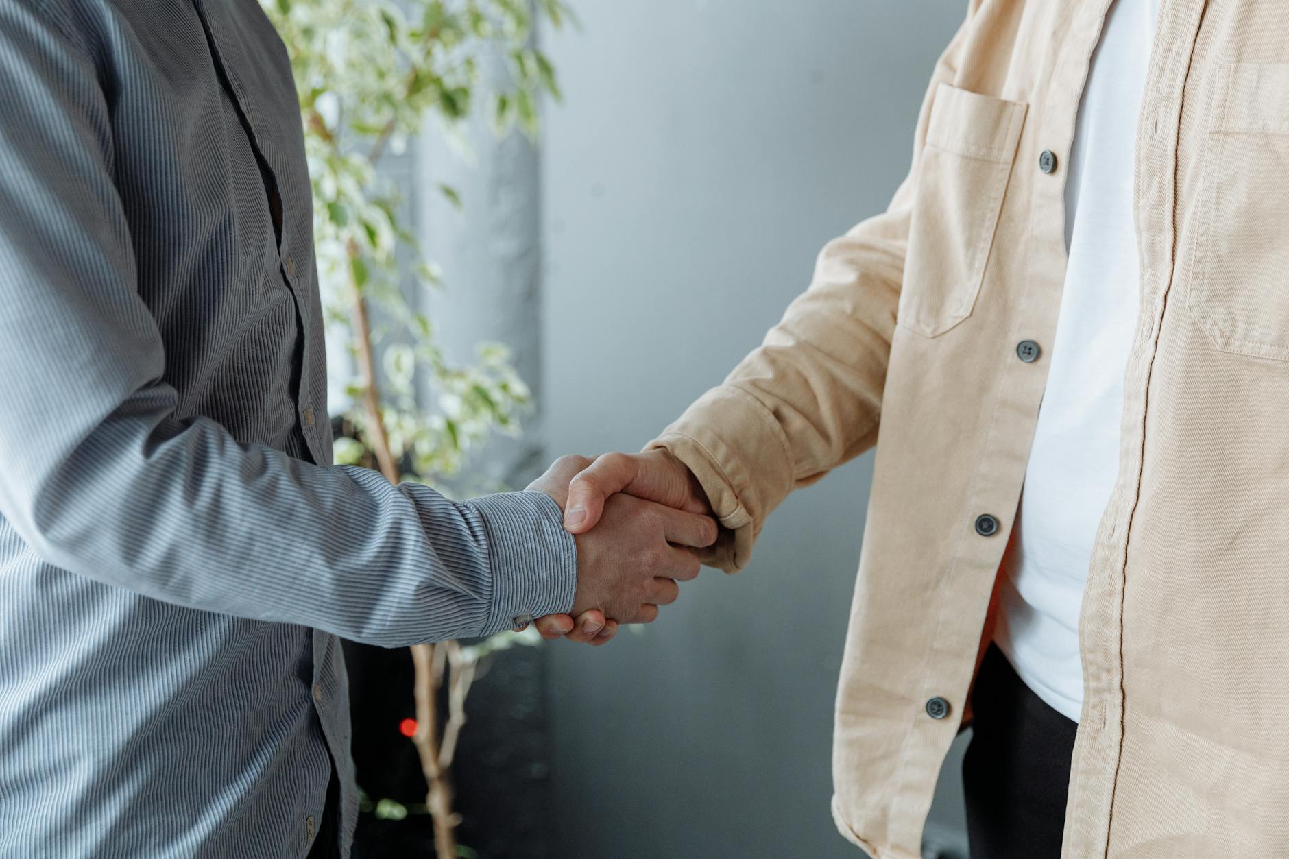 Two business professionals shaking hands over contract documents