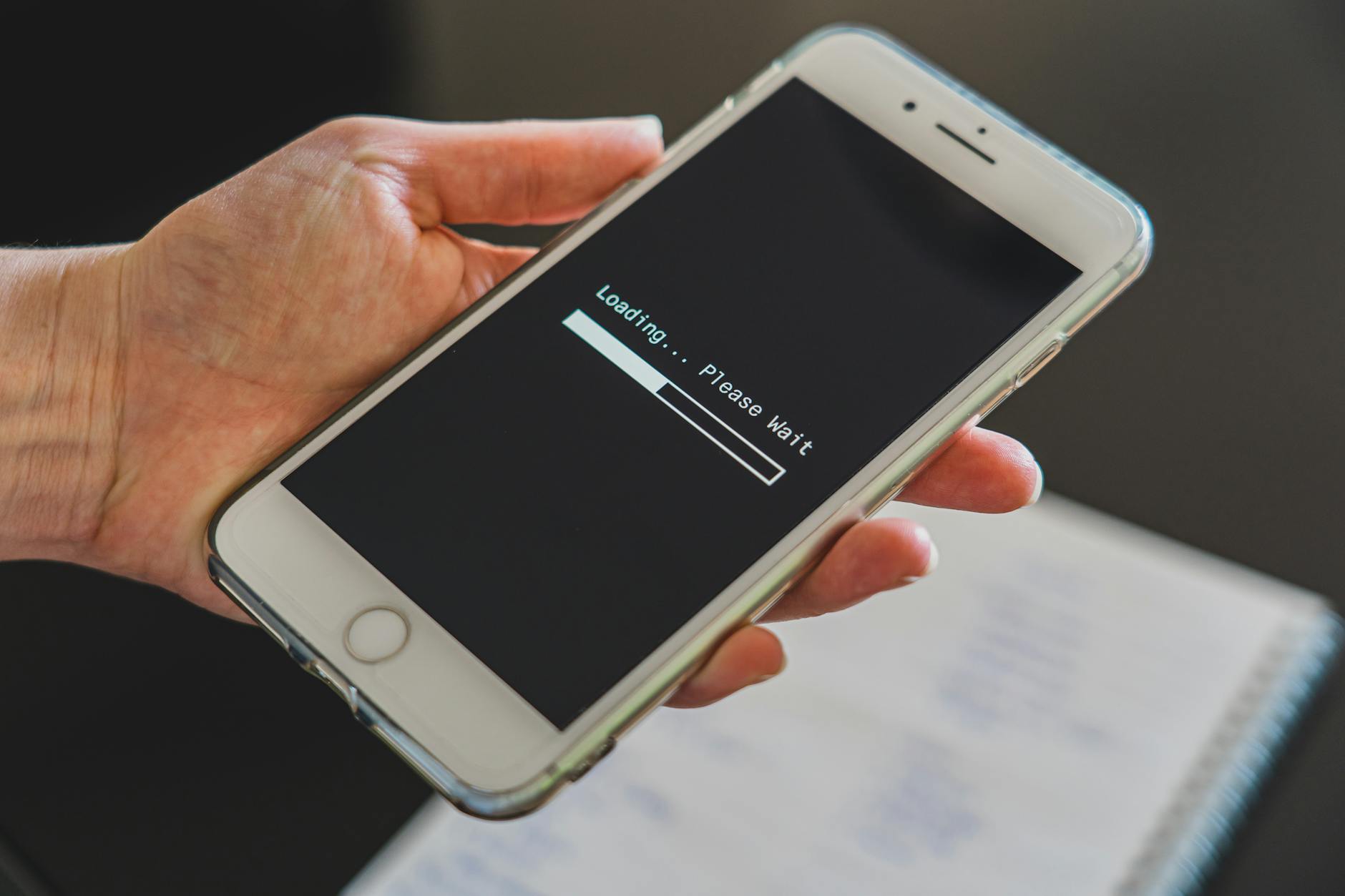 Person holding an iPhone displaying a software update screen