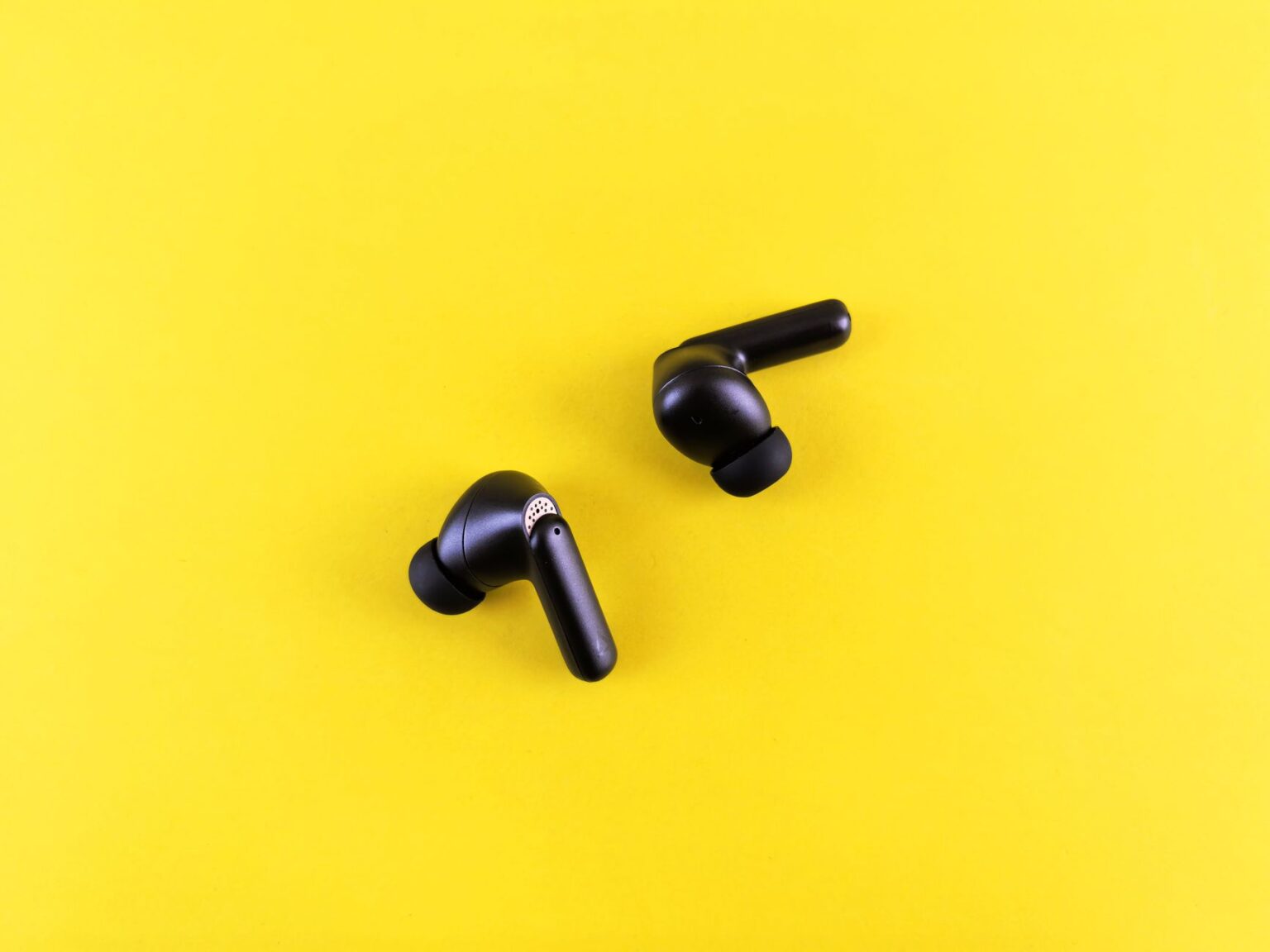 A pair of white wireless earbuds resting on a surface near their charging case