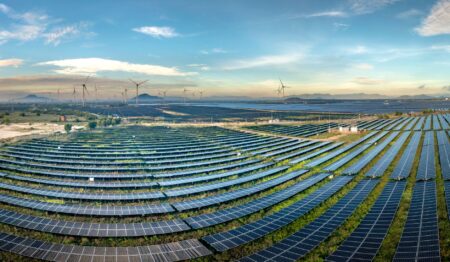 Large solar panels and wind turbines generating electricity across open land