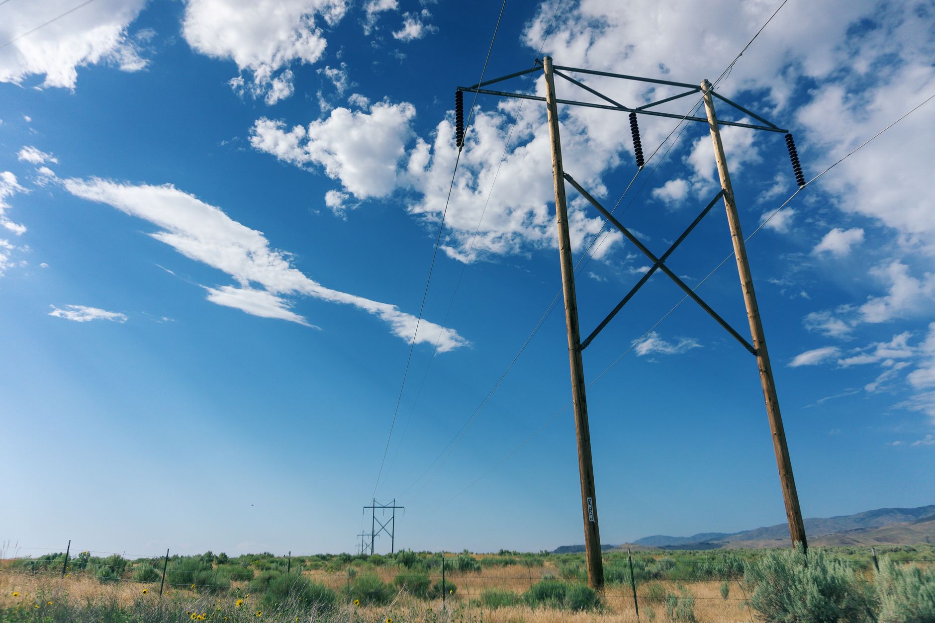 High-voltage electricity transmission towers against a hazy hot sky