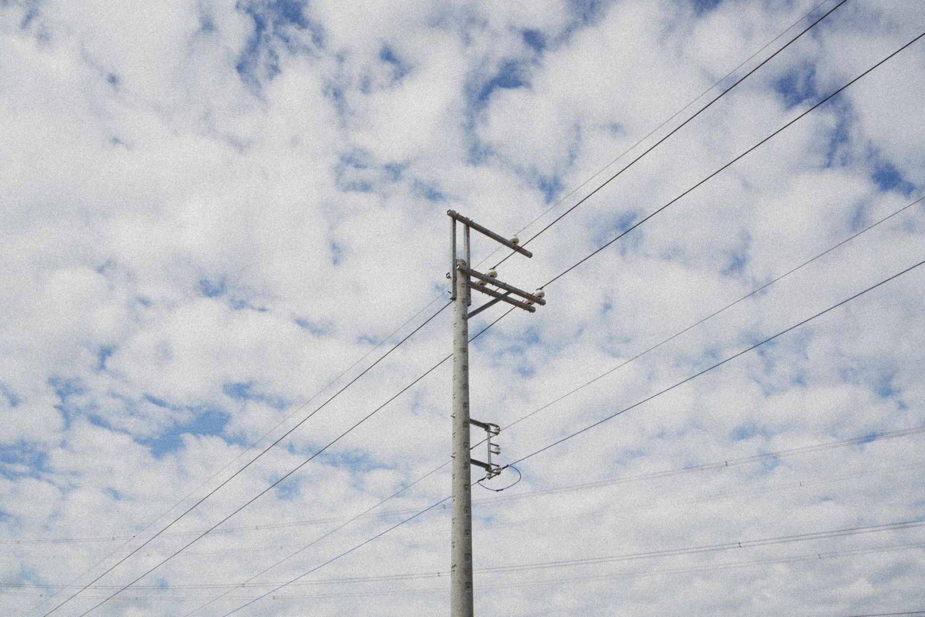High-voltage electricity transmission towers and power lines against a cloudy sky