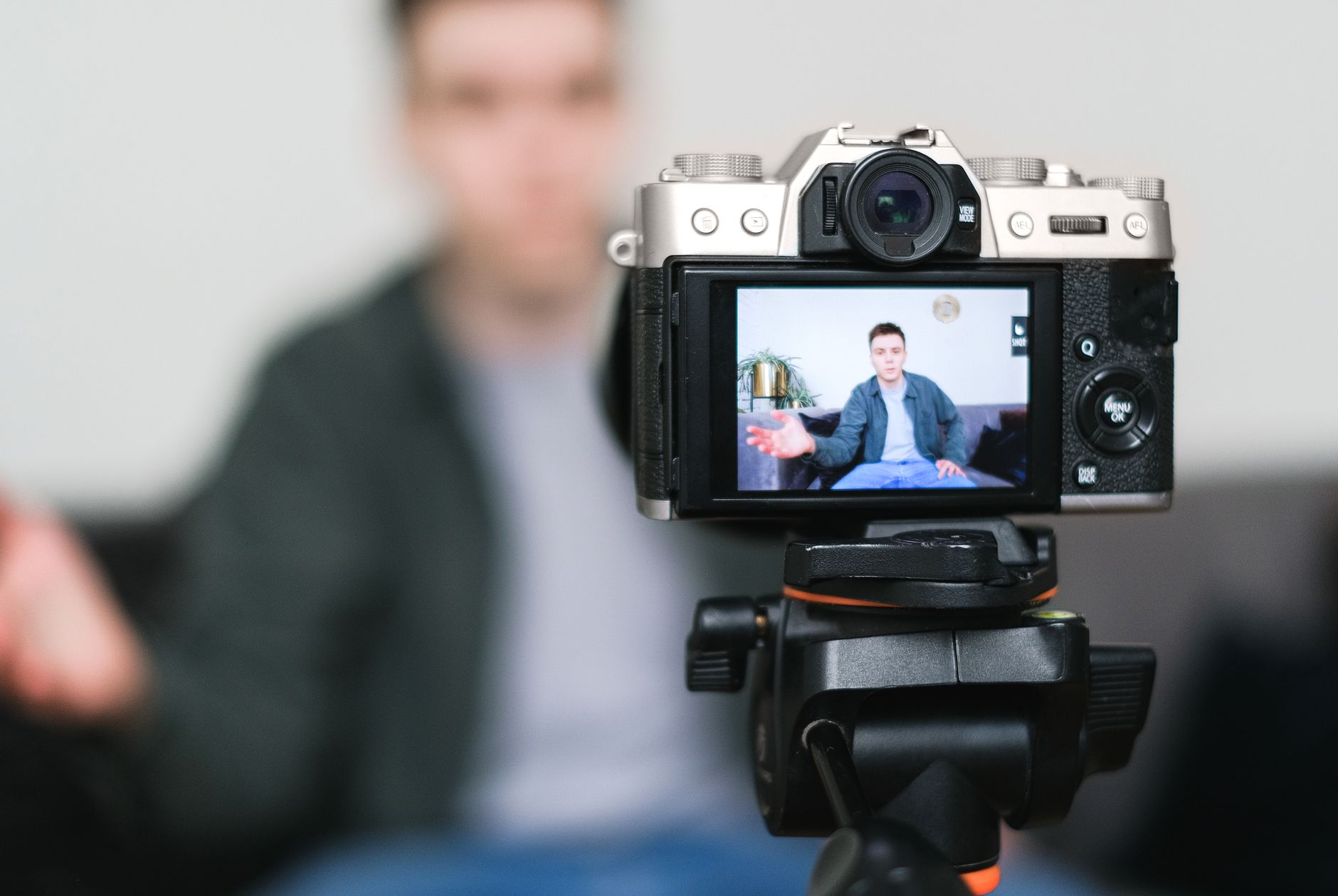 Content creator filming a video at a desk with a camera and laptop setup