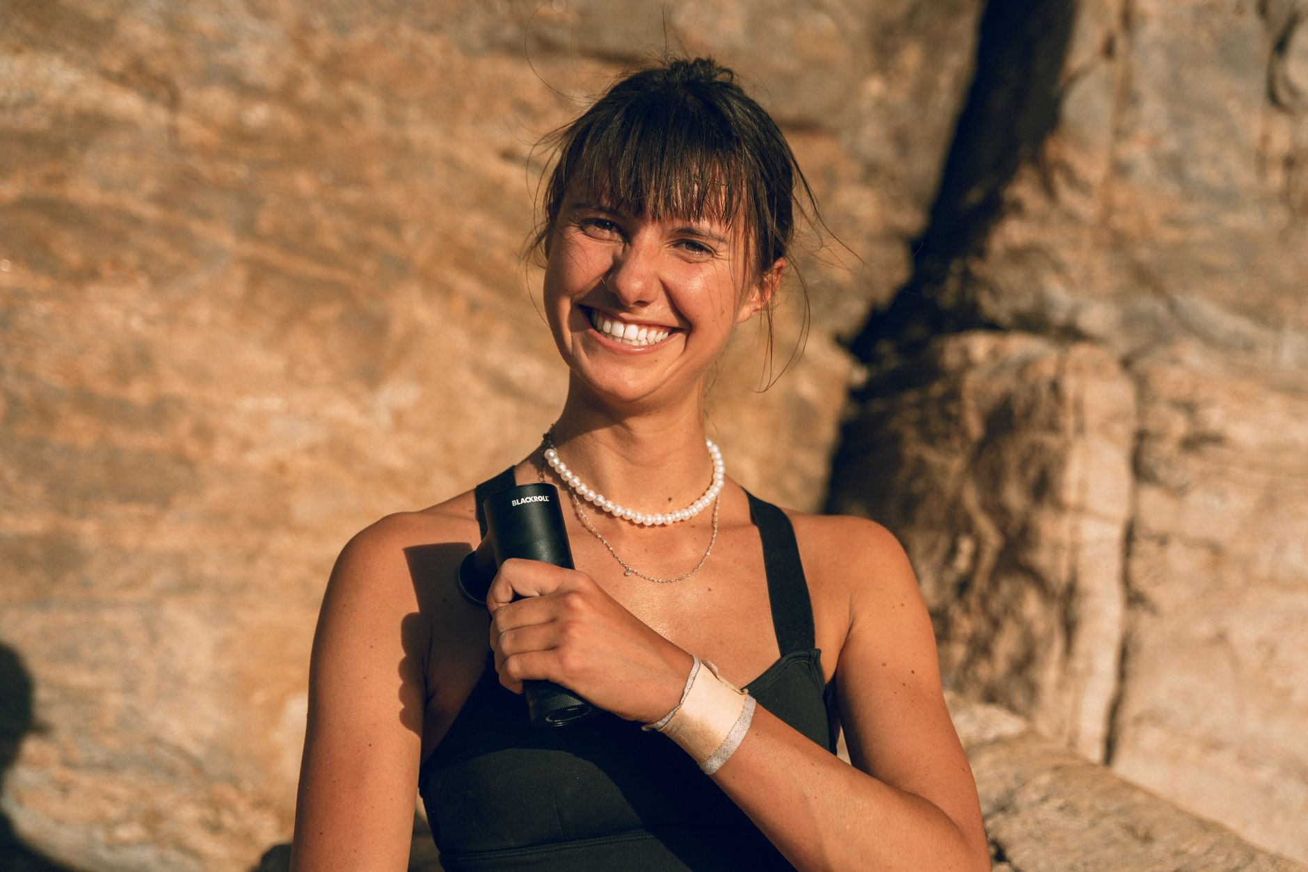 Athlete using a massage gun for muscle recovery after exercise
