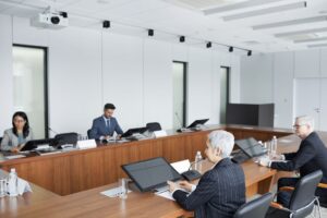 DeepMind CEO calls for an independent standards body to regulate frontier AI Business executives discussing regulatory policy in a formal boardroom setting