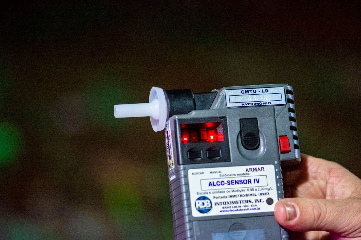 A Breathalyzer That Detects Fat Burning Is Now Handheld Person exhaling into a small handheld breathalyzer device for health monitoring