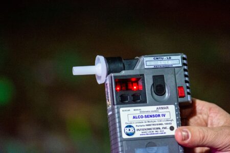 A Breathalyzer That Detects Fat Burning Is Now Handheld Person exhaling into a small handheld breathalyzer device for health monitoring