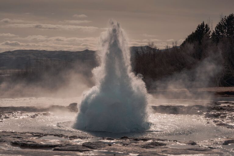 Steam rising from a geothermal power plant facility in a desert landscape