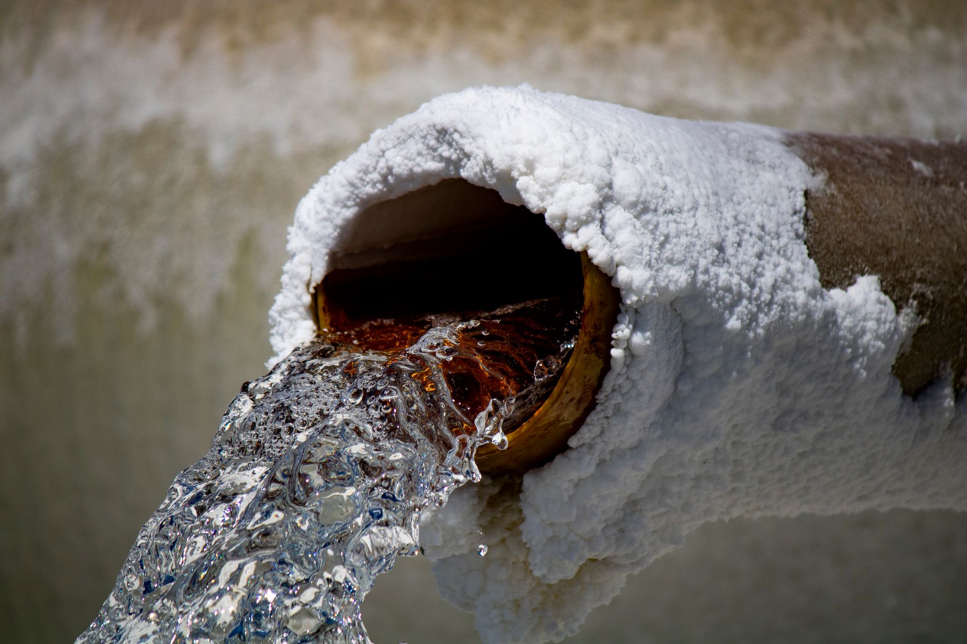 Water flooding a city street from a broken underground main