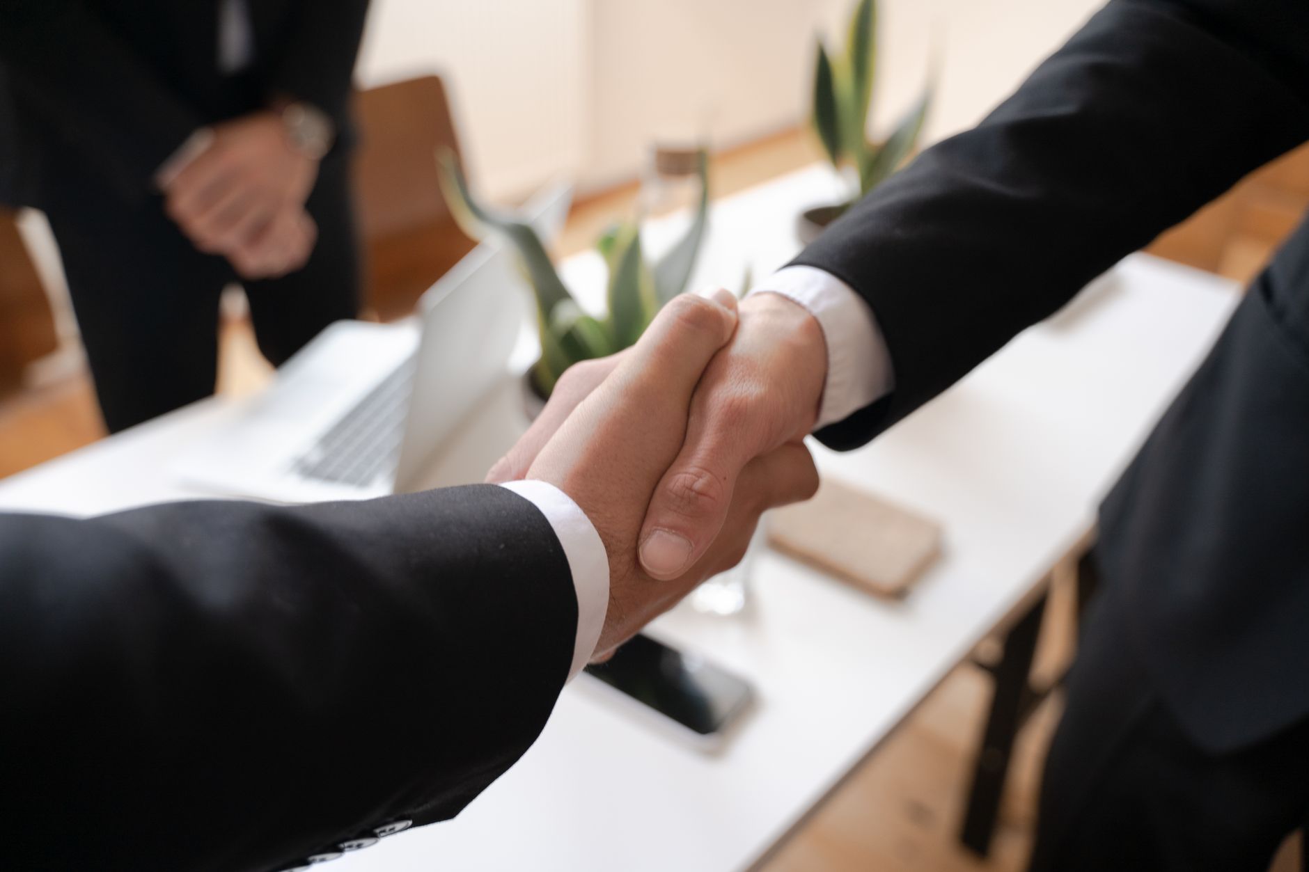 Two people shaking hands across a table representing a corporate settlement agreement