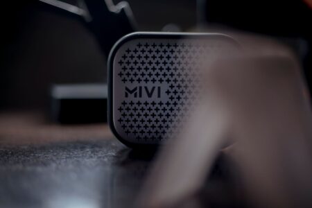 Portable Bluetooth speaker sitting on a wooden surface with soft background lighting