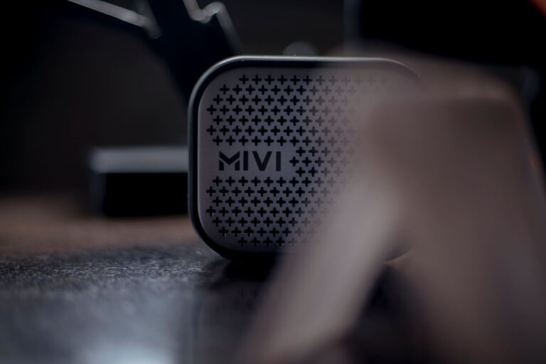 Portable Bluetooth speaker sitting on a wooden surface with soft background lighting