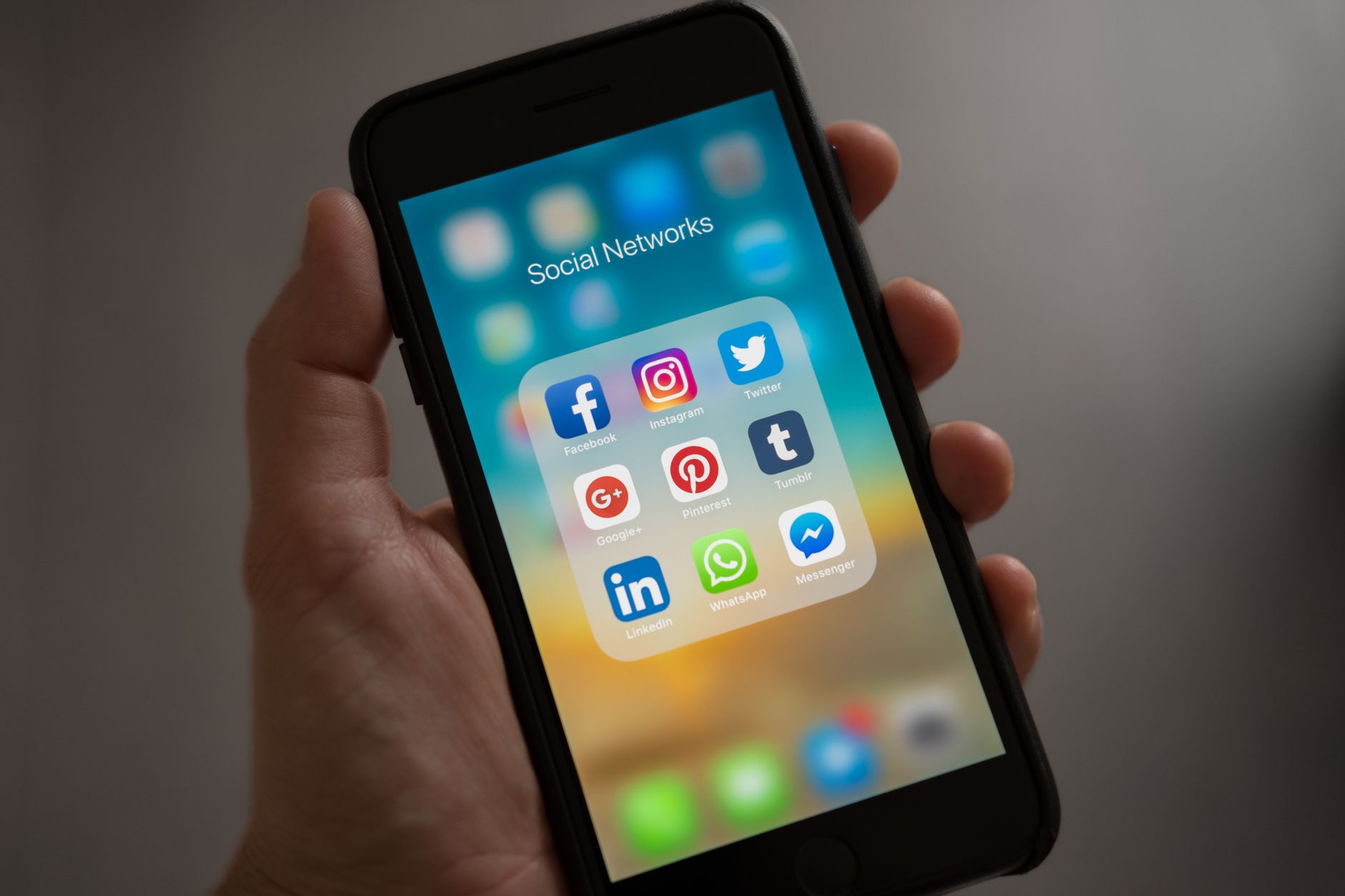 Person holding an iPhone against a neutral background