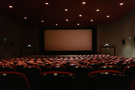 The IMAX Logo on Your Ticket May Not Mean What You Think Large movie theater screen viewed from audience seating in a dark auditorium