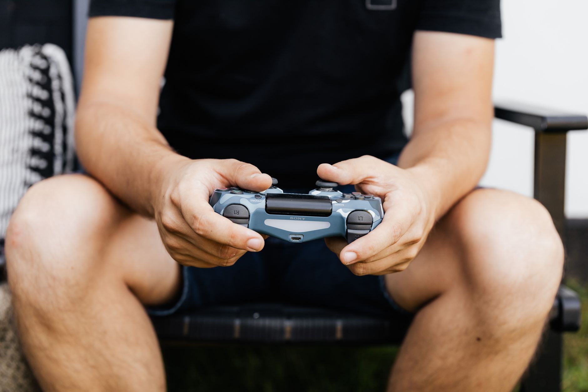 Person sitting on couch playing a video game console with a controller