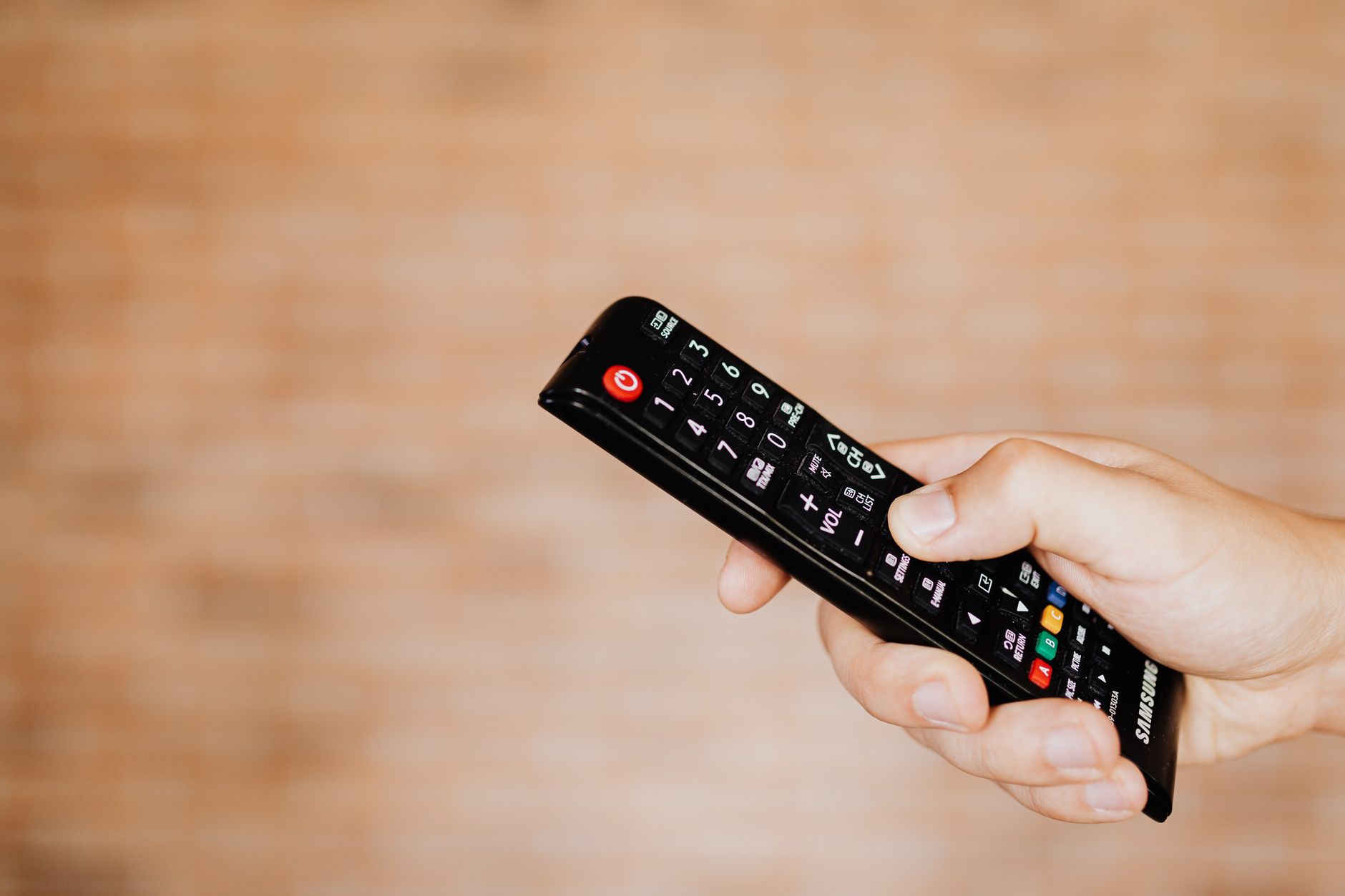 A person using a TV remote to navigate display settings on a smart television