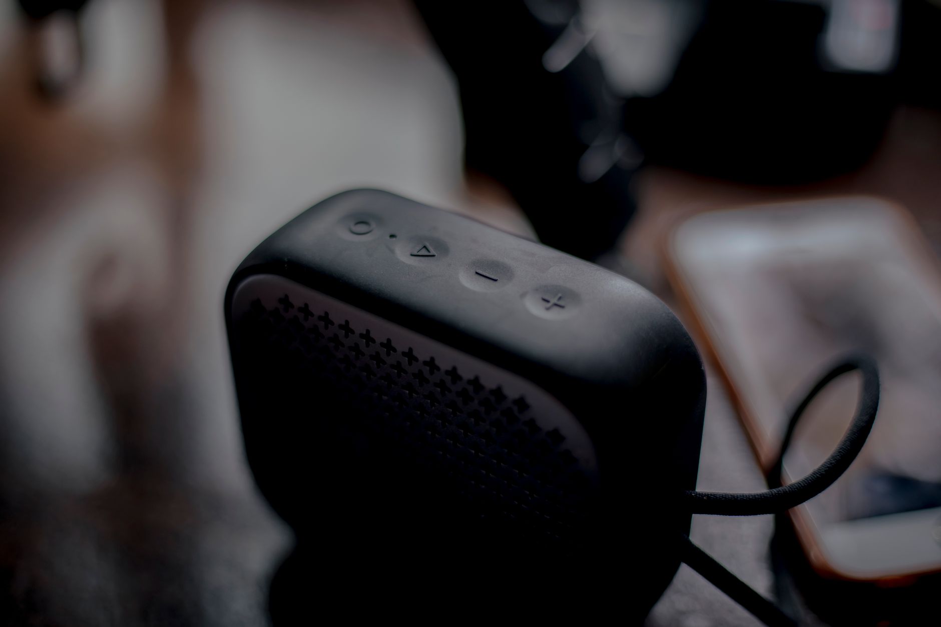 Smartphone connected to a small Bluetooth speaker outdoors on a table