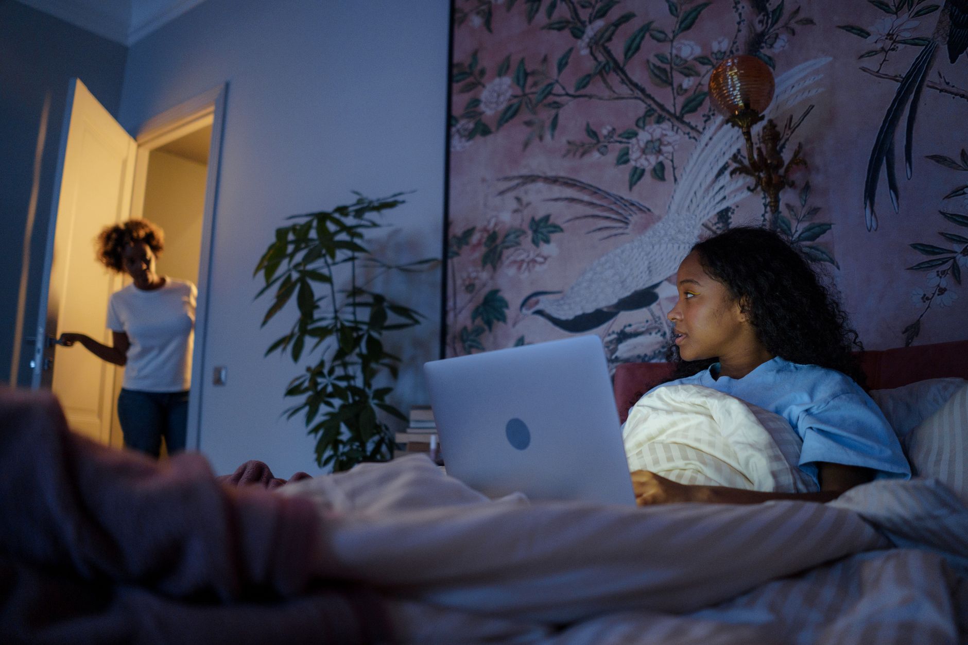 Teenager using a laptop alone in a dimly lit room