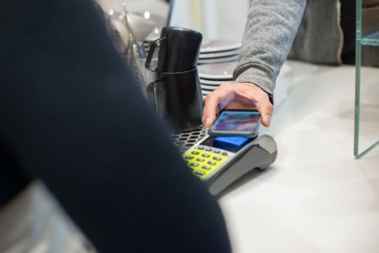 Google Wallet vs. Samsung Wallet: Where Each One Pulls Ahead Person holding a smartphone near a contactless payment terminal