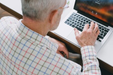 An aging laptop sitting on a wooden desk, showing signs of wear