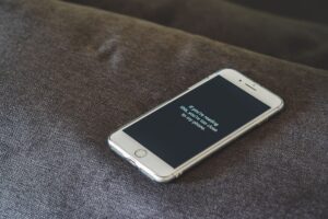 How to get your cut of Apple’s $250 million Siri settlement Person holding a smartphone with a privacy screen, representing mobile data concerns