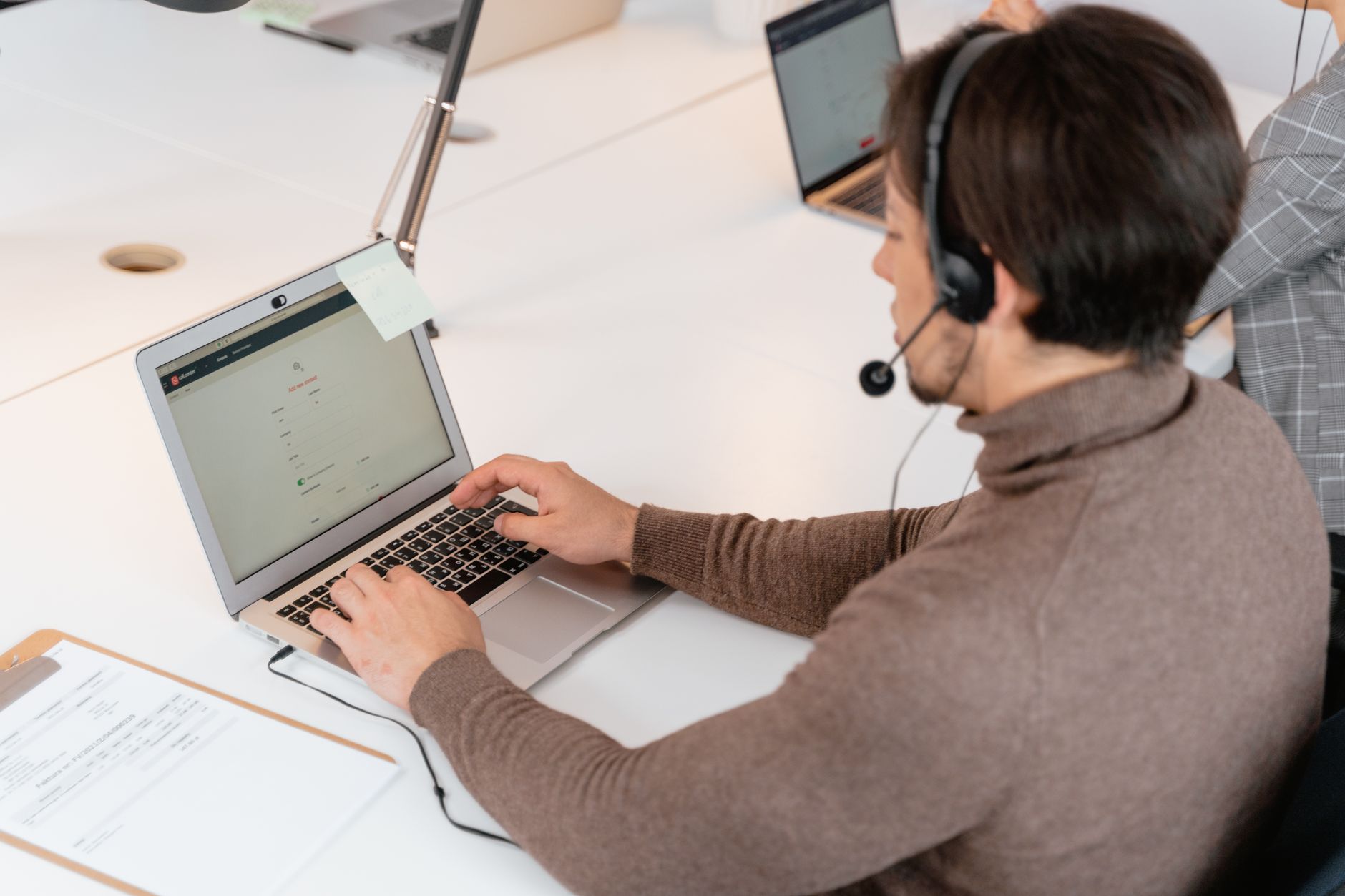 Person typing on a laptop in a dim room, phone beside them