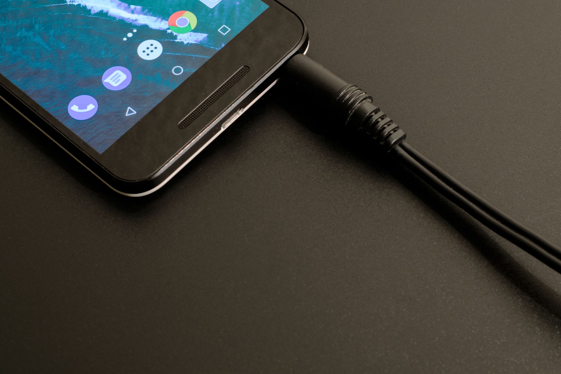 Smartphone connected to a charging cable on a wooden desk