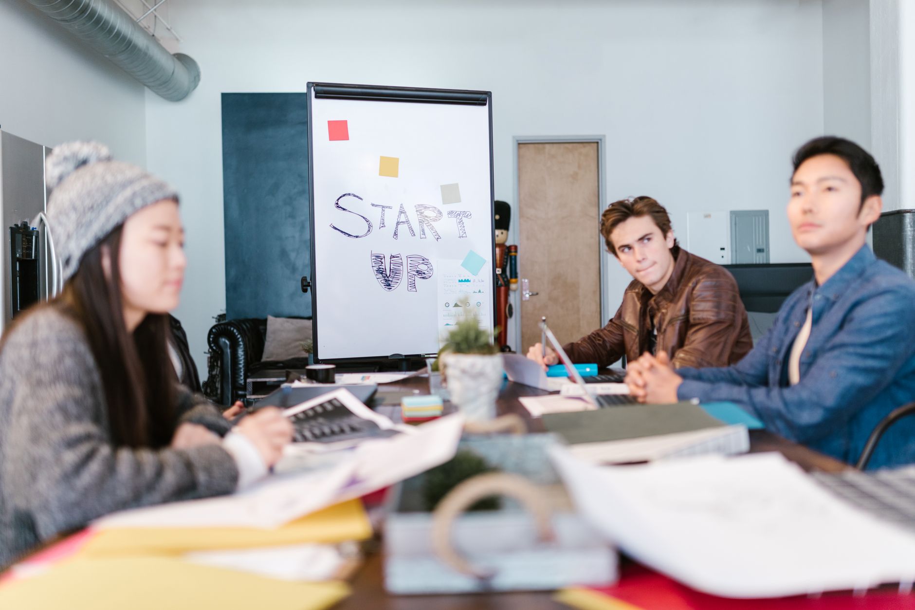 Founders in discussion at a startup workspace reviewing documents