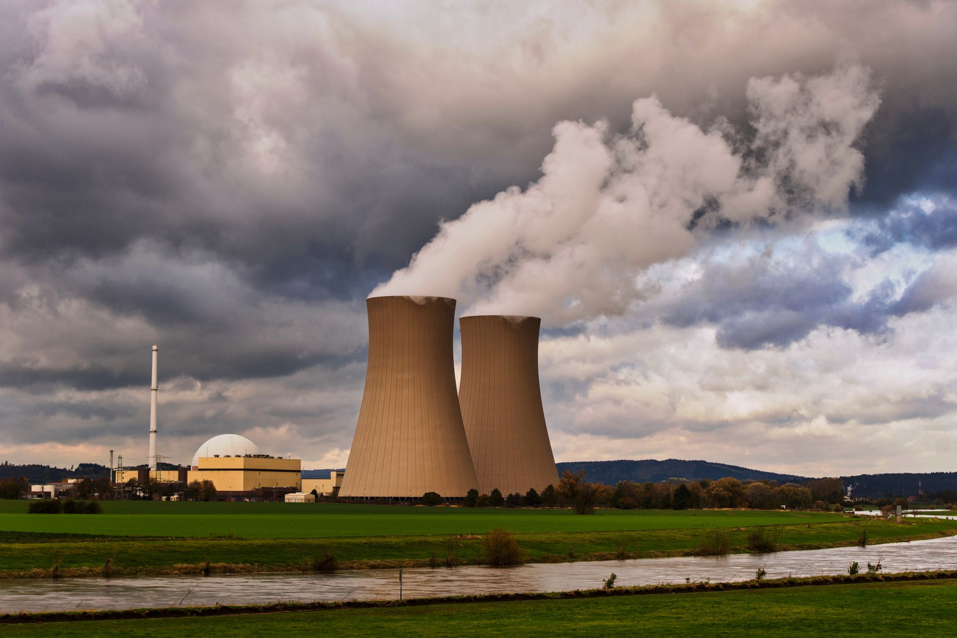 Nuclear power plant cooling towers producing steam against a cloudy sky