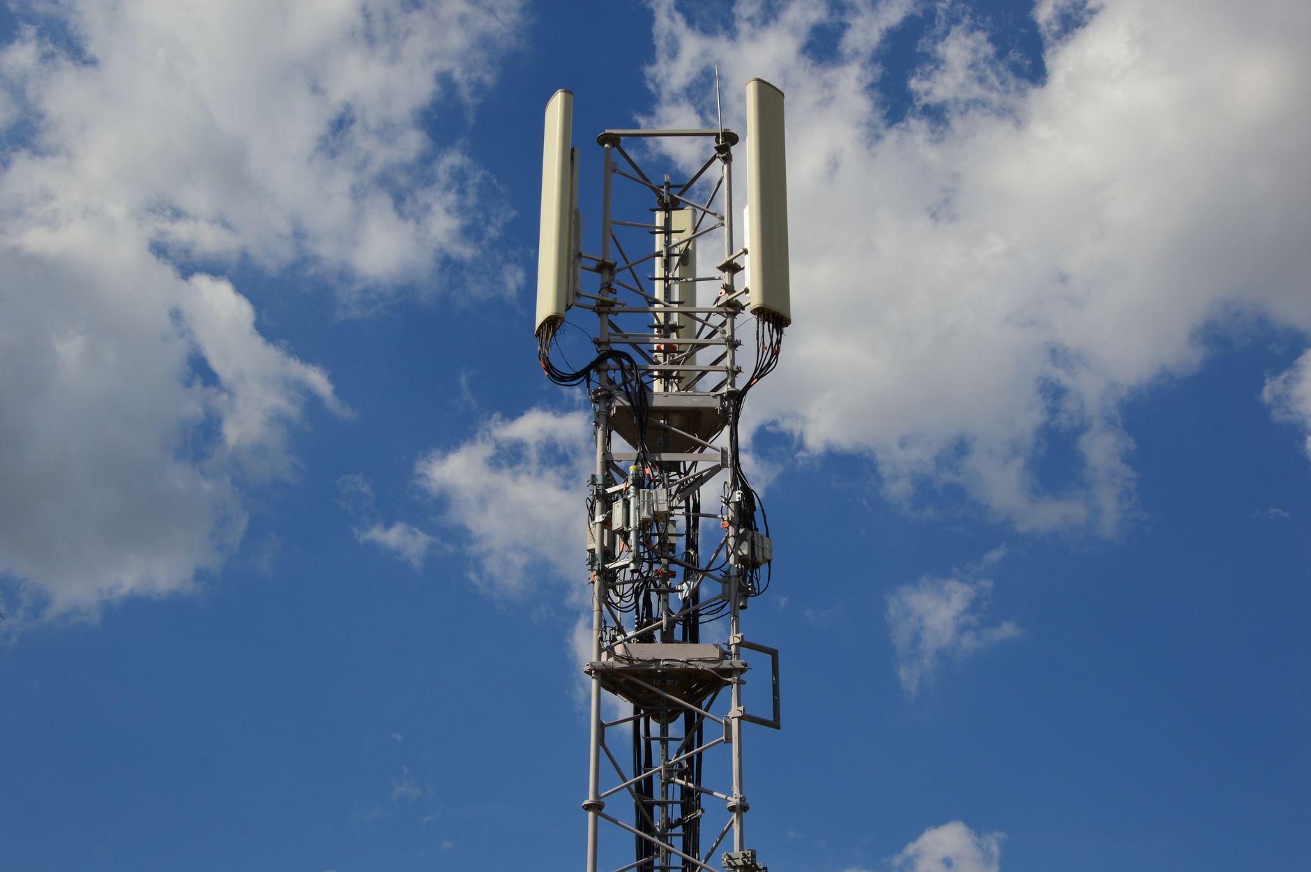 A 5G cellular tower in an urban environment against a blue sky