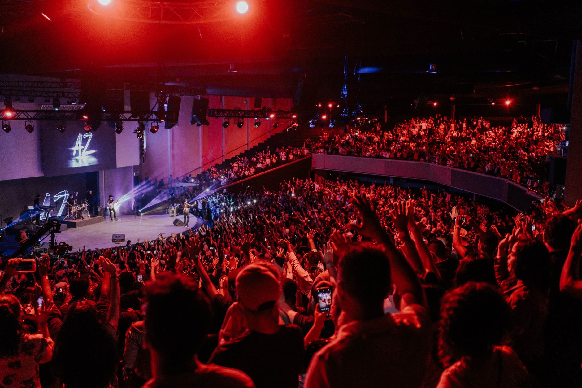Audience seated in a dark theater during a live stage performance